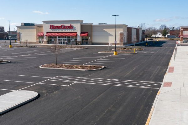 Pristine asphalt parking lot and cleared concrete sidewalks outside a commercial retail shopping center after seasonal site maintenance.